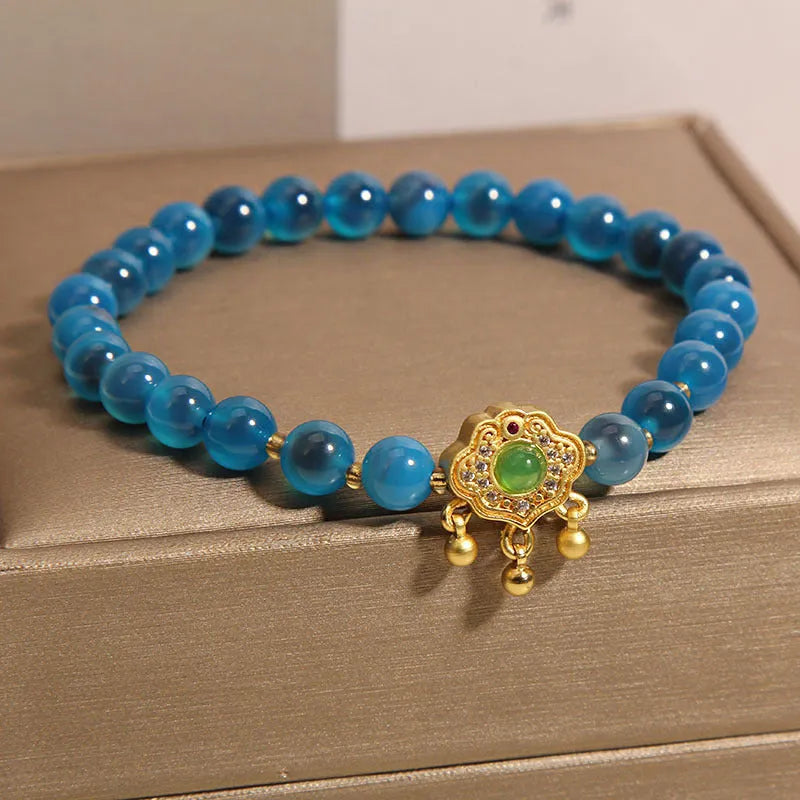 Close-up of a women's bracelet with a blue sugar heart agate safety lock pendant, crystal links, and rhinestone details.