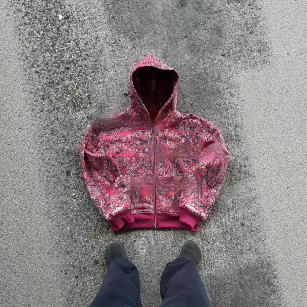 A man's loose-fitting zip-up hooded coat in red or blue with a digital print design.