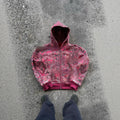 A man's loose-fitting zip-up hooded coat in red or blue with a digital print design.