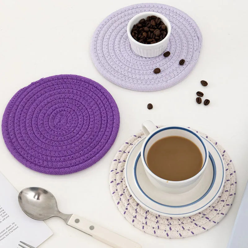 Set of three round cotton cord coasters in blue colour, 18cm diameter, on a table.