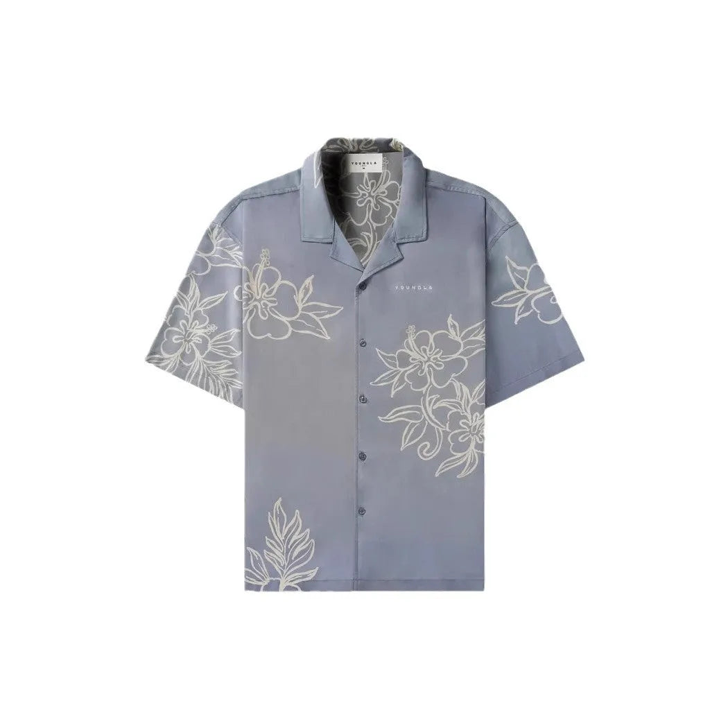 Man wearing a loose grey short-sleeve top with a floral print pattern.