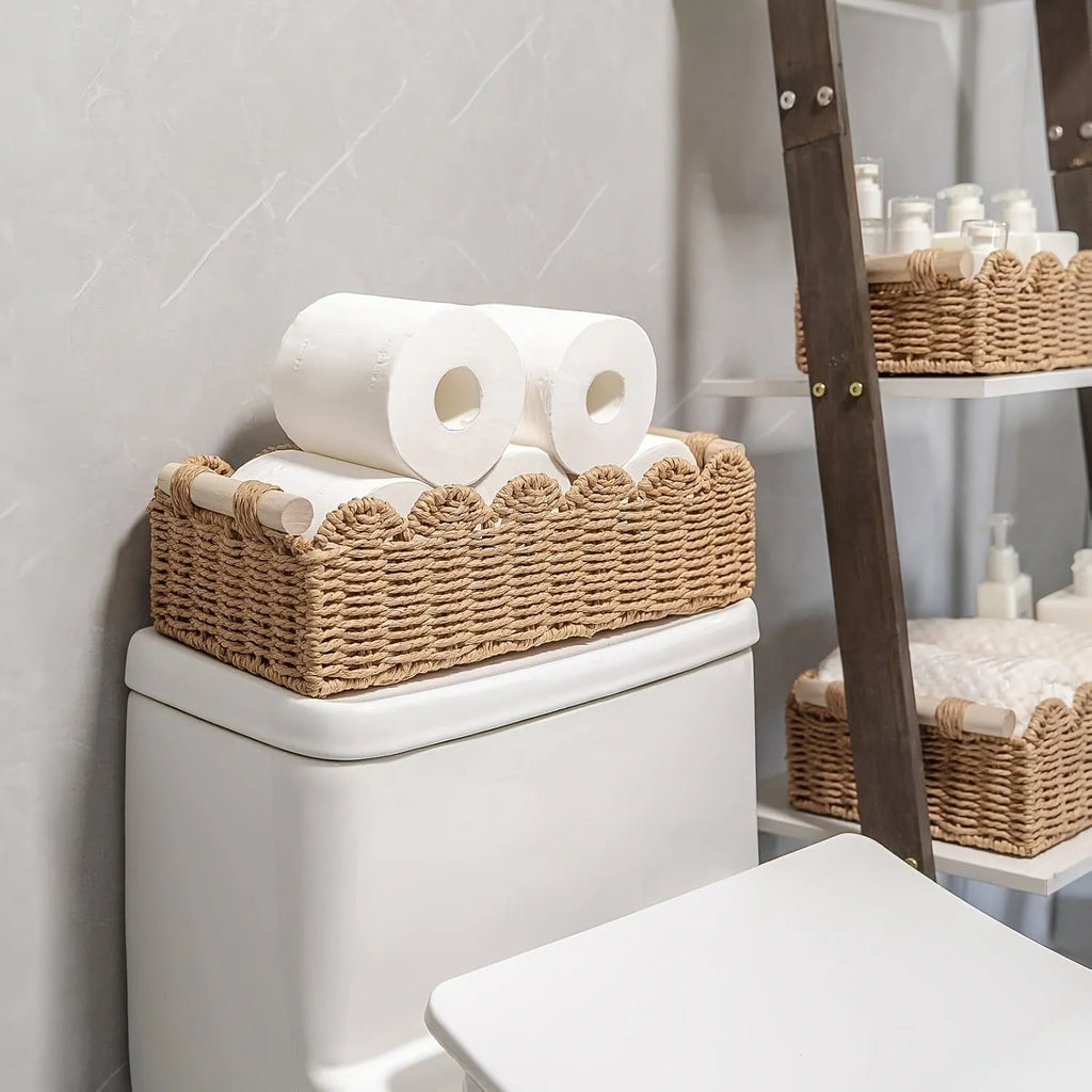 Modern simple woven paper storage basket in neutral colour on a wooden desktop holding remote controls and pens.