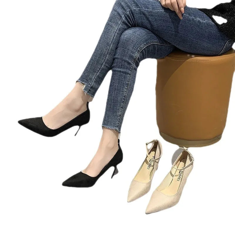 Women's black stiletto pump with buckle closure and skull pattern, shown on a foot.