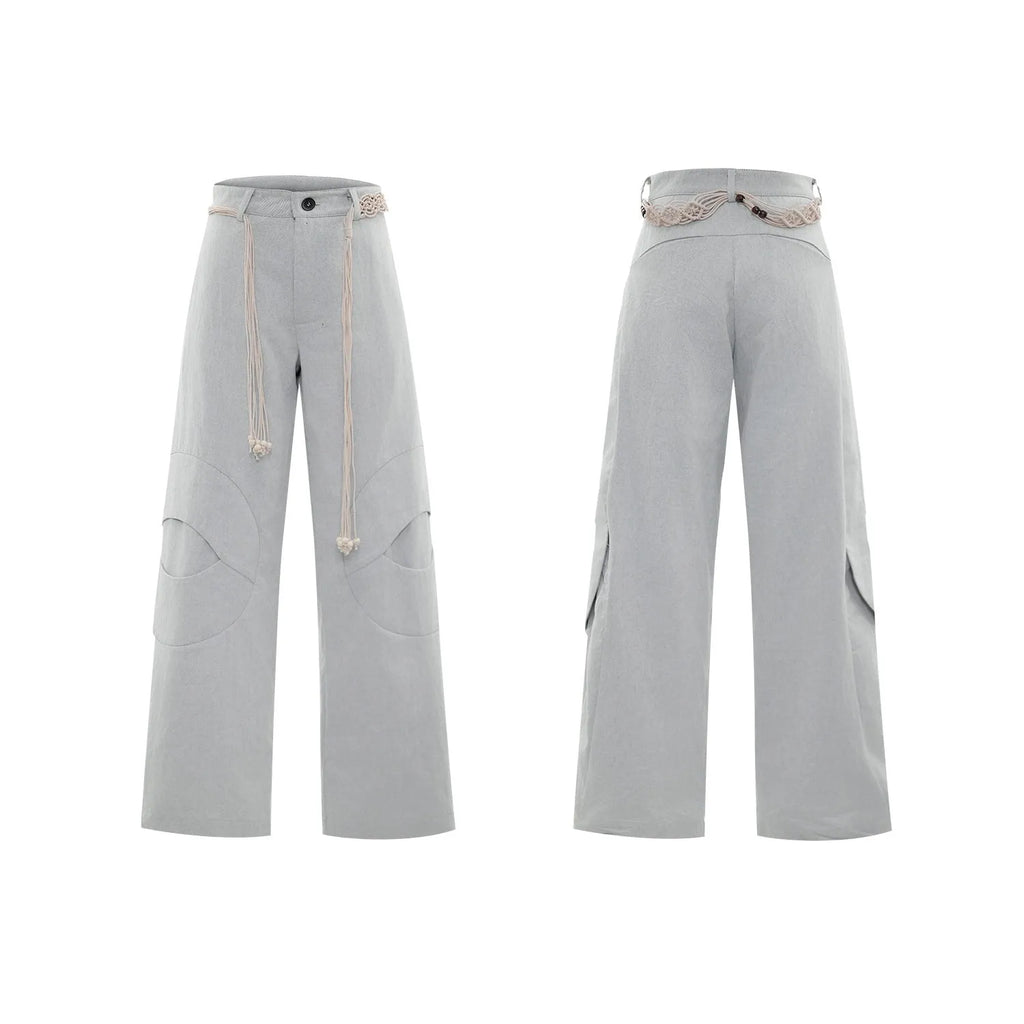 Man wearing dark grey straight-leg cotton trousers with a tassel detail and loose fit.