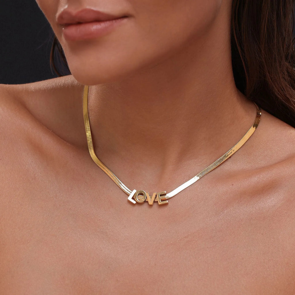 A gold and a silver titanium steel necklace with letter and number pendants on a 40.5cm chain.