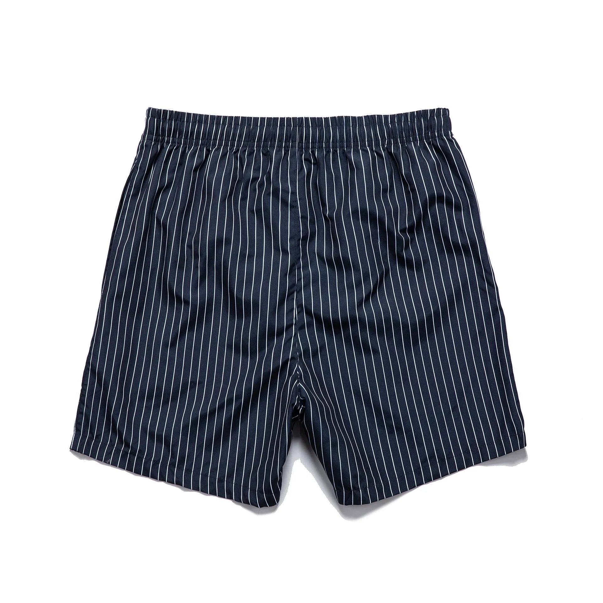 Man wearing grey striped polyester beach shorts with a straight leg opening, on a beach.