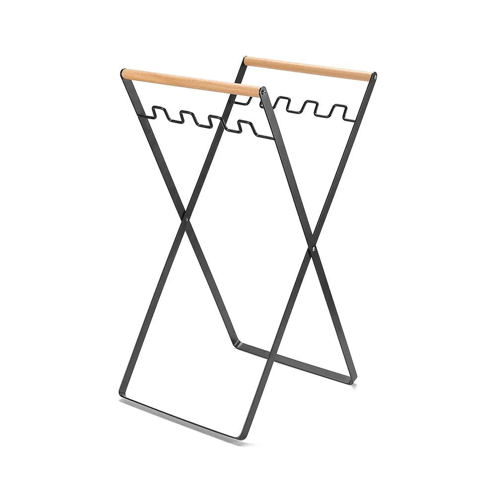 Black foldable outdoor iron trash rack with wooden handle holding a white bin bag.