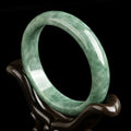 A simple deep pea green ring bracelet for women on a white background, showing its adjustable size.