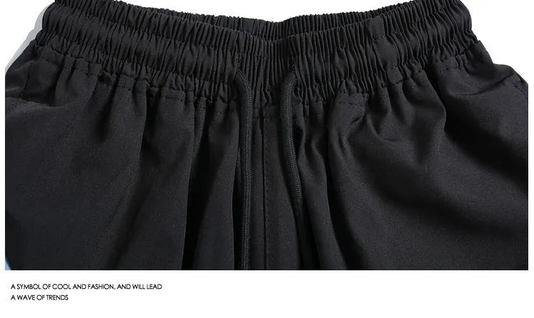 Men's black loose fit sports shorts with elastic waistband and contrast trim, shown on a hanger.