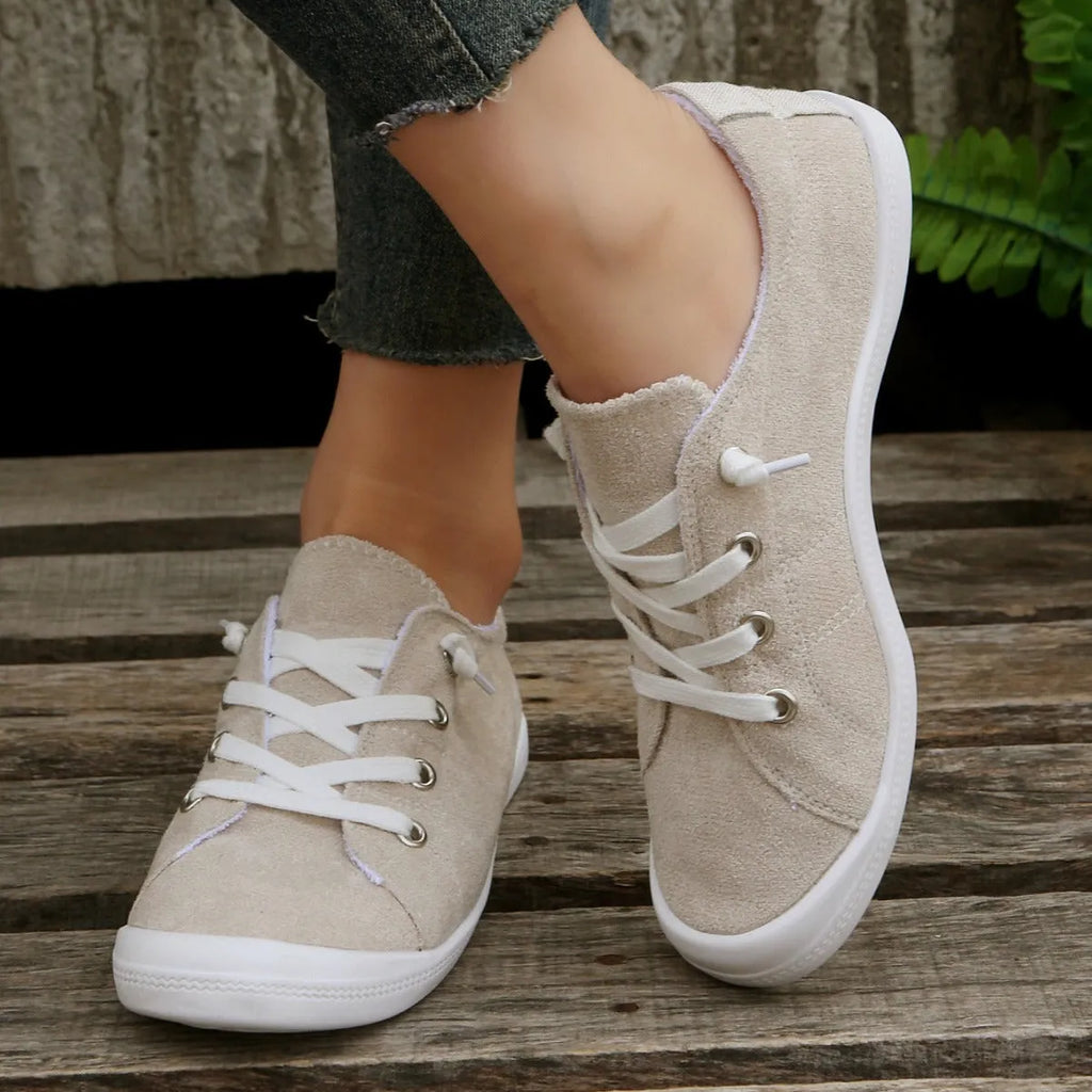 Women's creamy white beige fabric low-top casual sneakers with a rubber sole on a plain background.