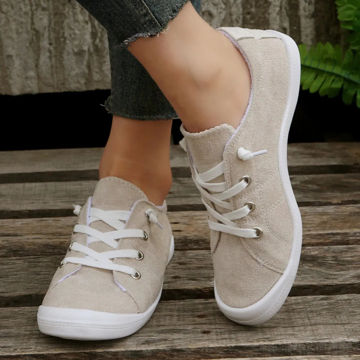 Women's creamy white beige fabric low-top casual sneakers with a rubber sole on a plain background.