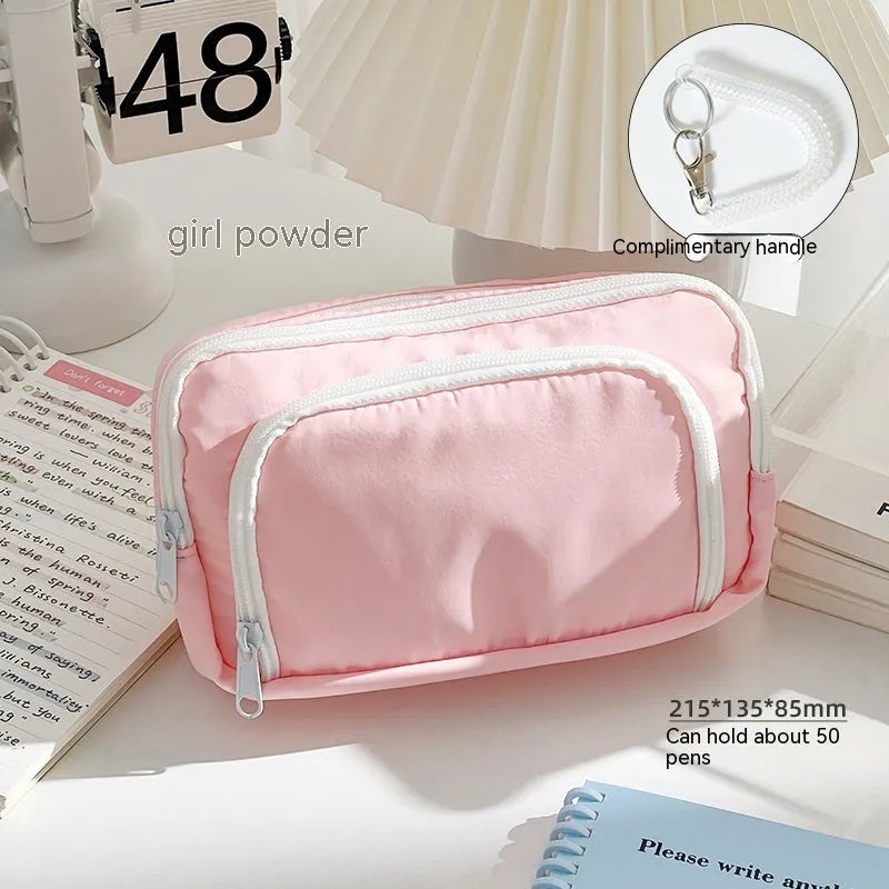 Double layer zippered pencil case in blue with a gift handle, shown next to pens and pencils.