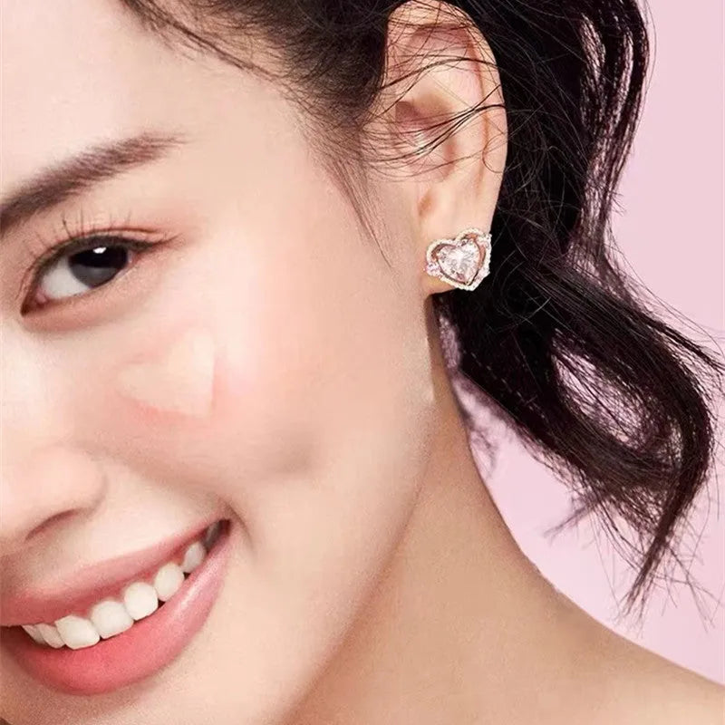A pair of white heart-shaped stud earrings for women on a plain background.