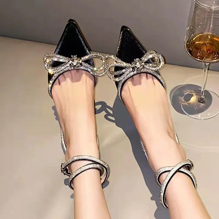Women's black stiletto heel sandals with a silk back bandage and pointed toe, showing buckle fastening.