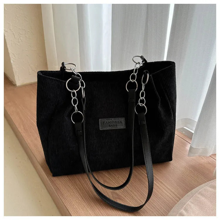 Corduroy one-shoulder tote handbag in a horizontal square shape with a three-dimensional outer pocket.