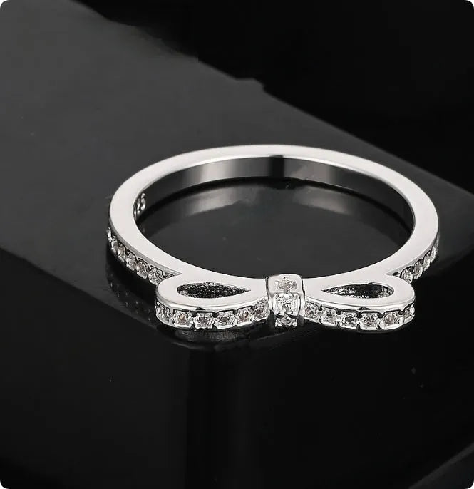 Silver plated bow-shaped ring with clear rhinestone crystal decoration on a model finger