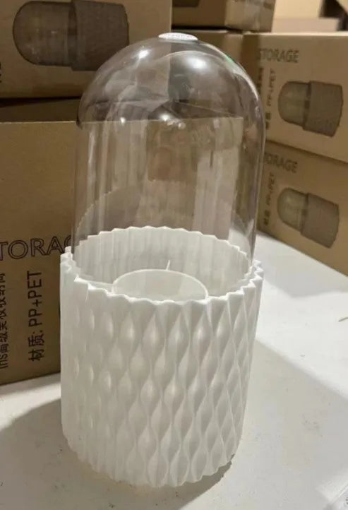 White transparent acrylic makeup brush holder with lid on a desktop, showing rotating base.
