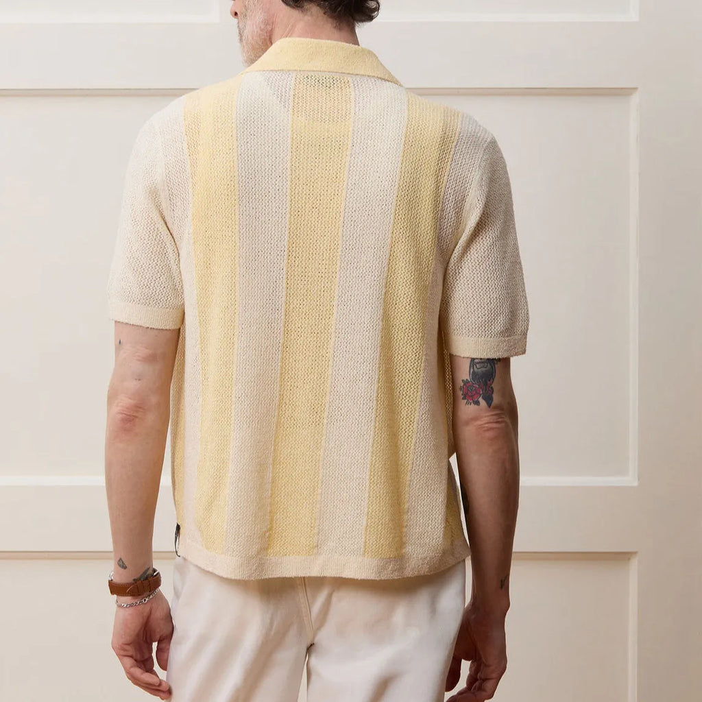 A bright yellow men's short-sleeved polo shirt with hollow-out asymmetric patterning on a casual model.