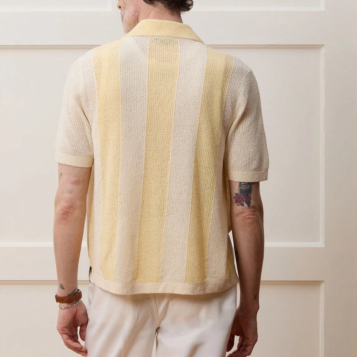 A bright yellow men's short-sleeved polo shirt with hollow-out asymmetric patterning on a casual model.