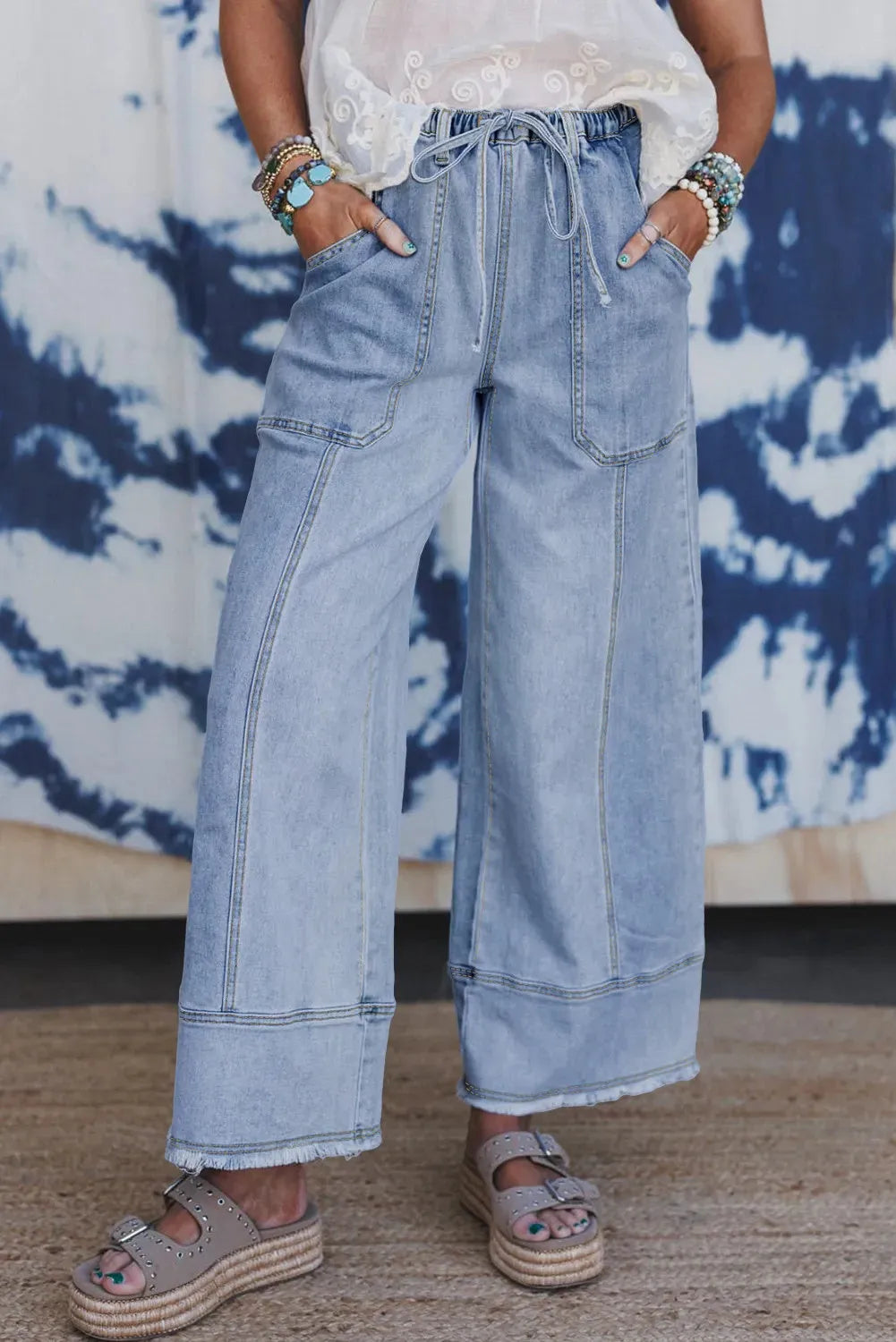 Beau blue wide leg denim trousers with a drawstring waist and raw hem detailing.