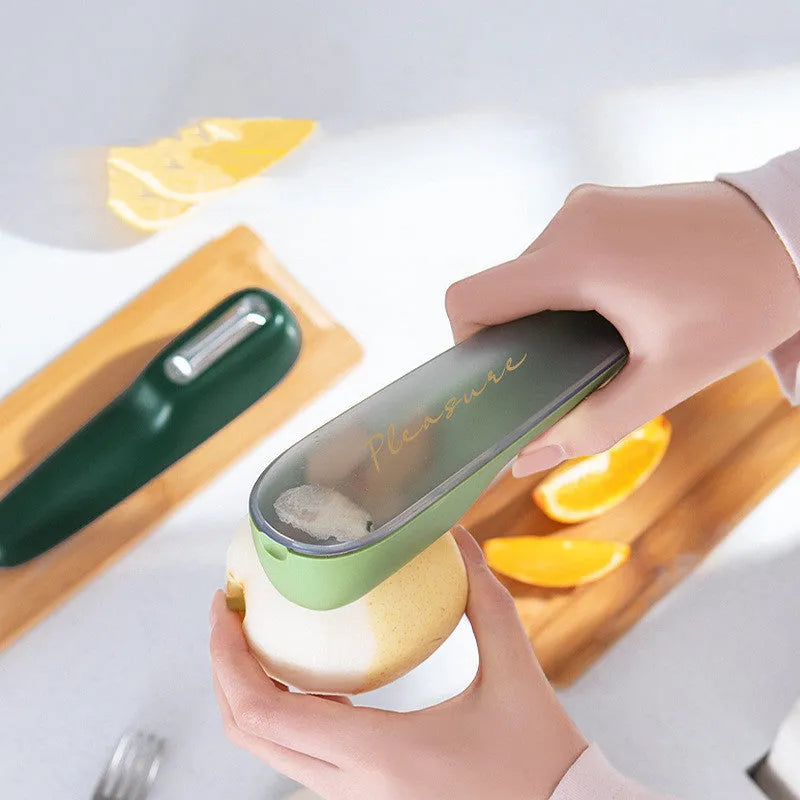 Dark green vegetable peeler with a storage tube and stainless steel blade on a kitchen worktop.
