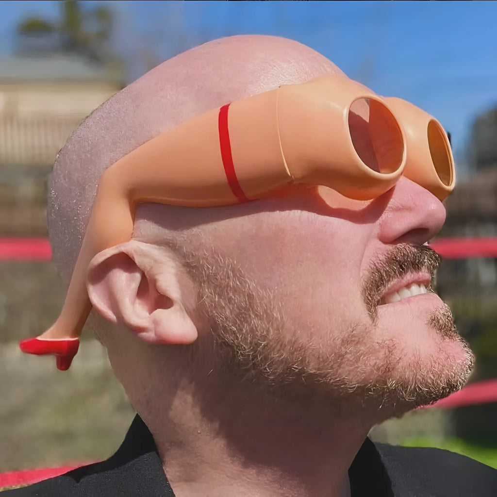 Orange plastic novelty sunglasses with a leg hip frame design on a white background.