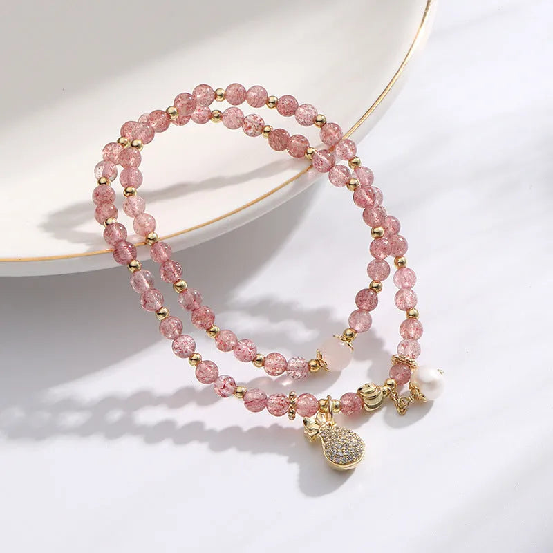 Close-up of a women's geometric bracelet made from pink strawberry quartz crystals.