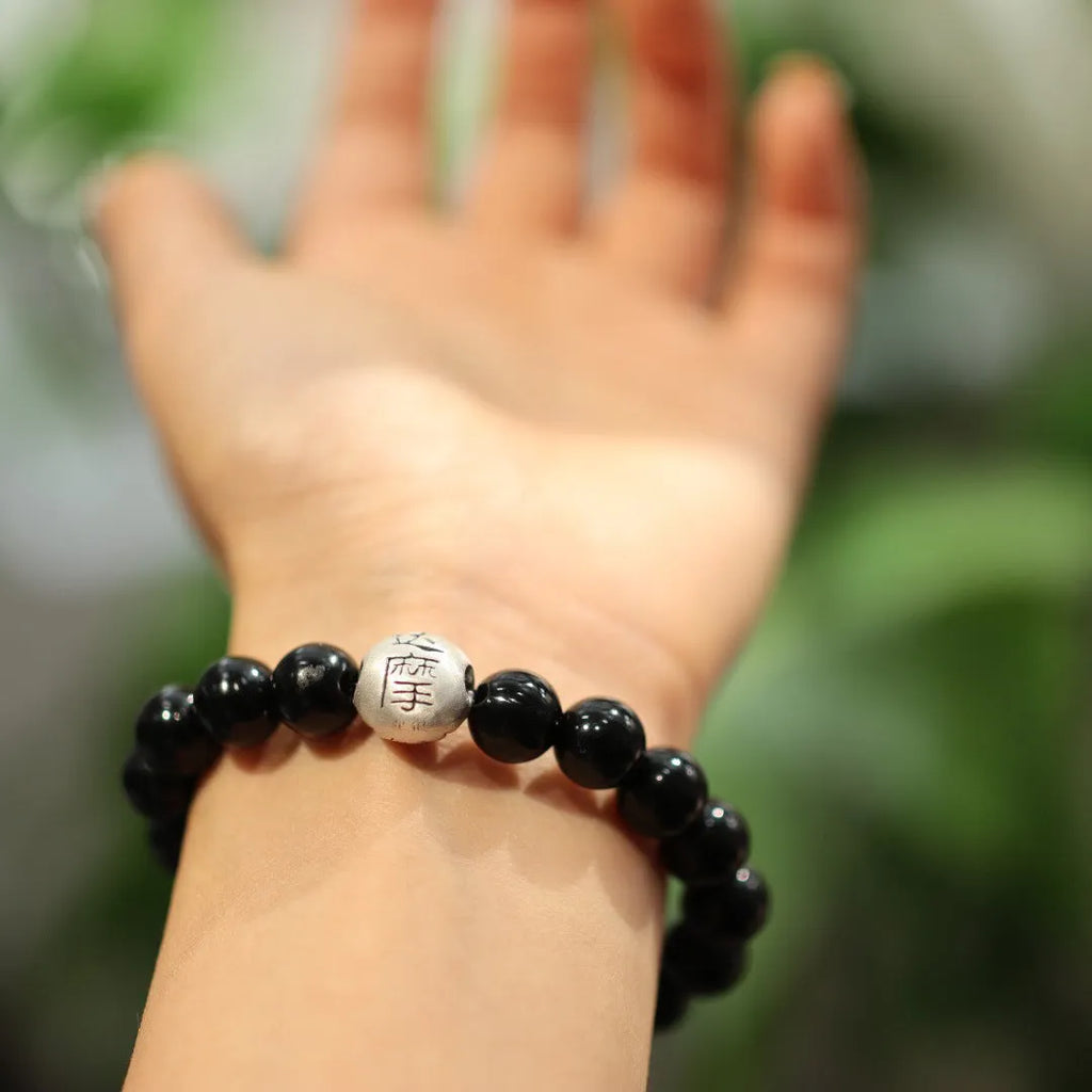 Close-up of a black agate and sterling silver bracelet showing 10mm beads and detailed clasp.