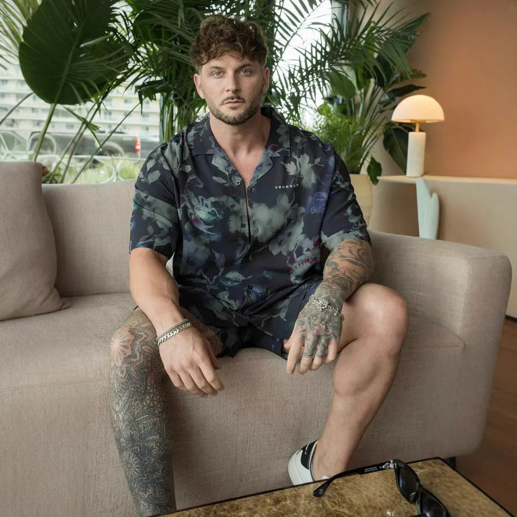 Man wearing a loose grey short-sleeve top with a floral print pattern.