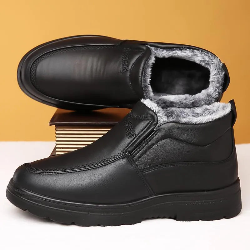 Men's black fleece-lined slip-on winter shoes with a rubber sole on a grey background.