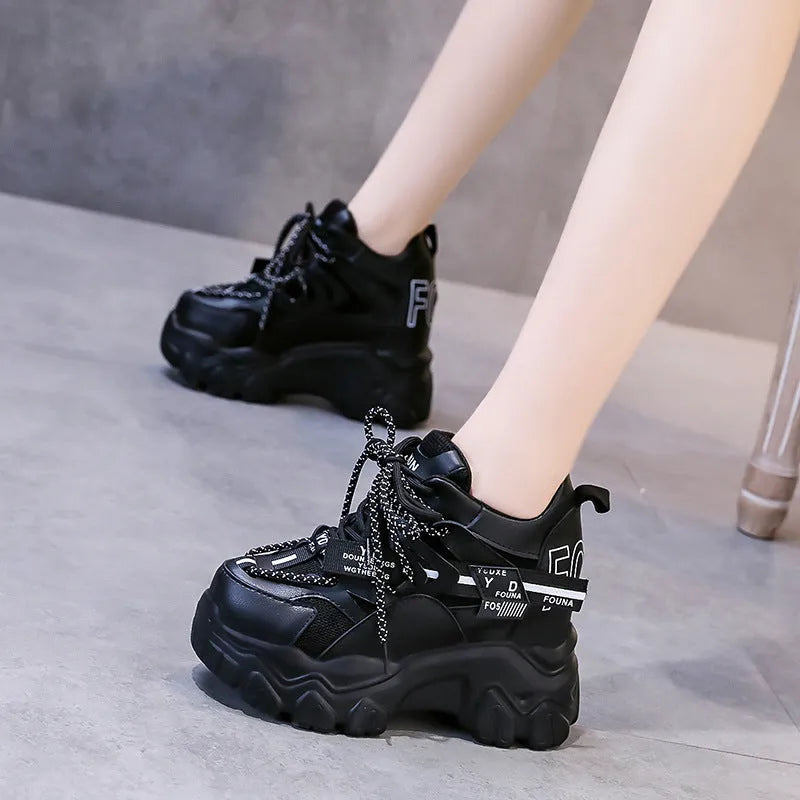 Women's white low-top platform trainers with mesh panels and a black cross-strap over the vamp.