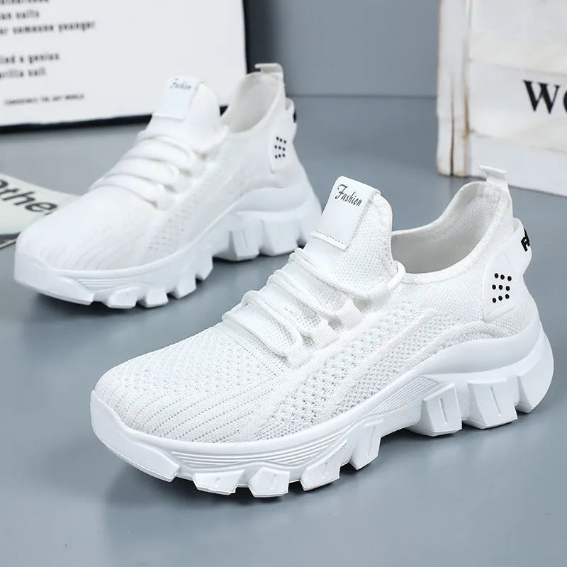 Women's white Flyknit running sneakers with thick PVC sole and lace-up front on a beige background.