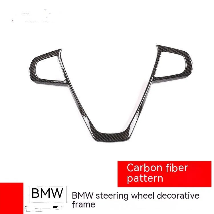 Black carbon fibre pattern button frame for BMW steering wheel, shown as a single clip-on trim piece.