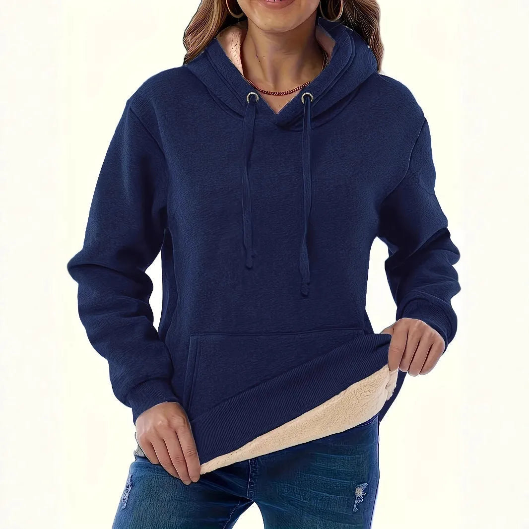 Woman wearing a loose black hooded sweater with a raised 3D pattern on the fabric.