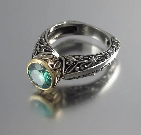 Flower-shaped vintage ring with gold-plated details and a green gemstone on a silver-toned alloy band.