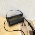 Men's cylindrical leather crossbody phone bag in black, shown with visible stitching and shoulder strap