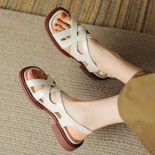 Women's black patent leather square toe beach sandals with cross-band strap on a low rubber sole.