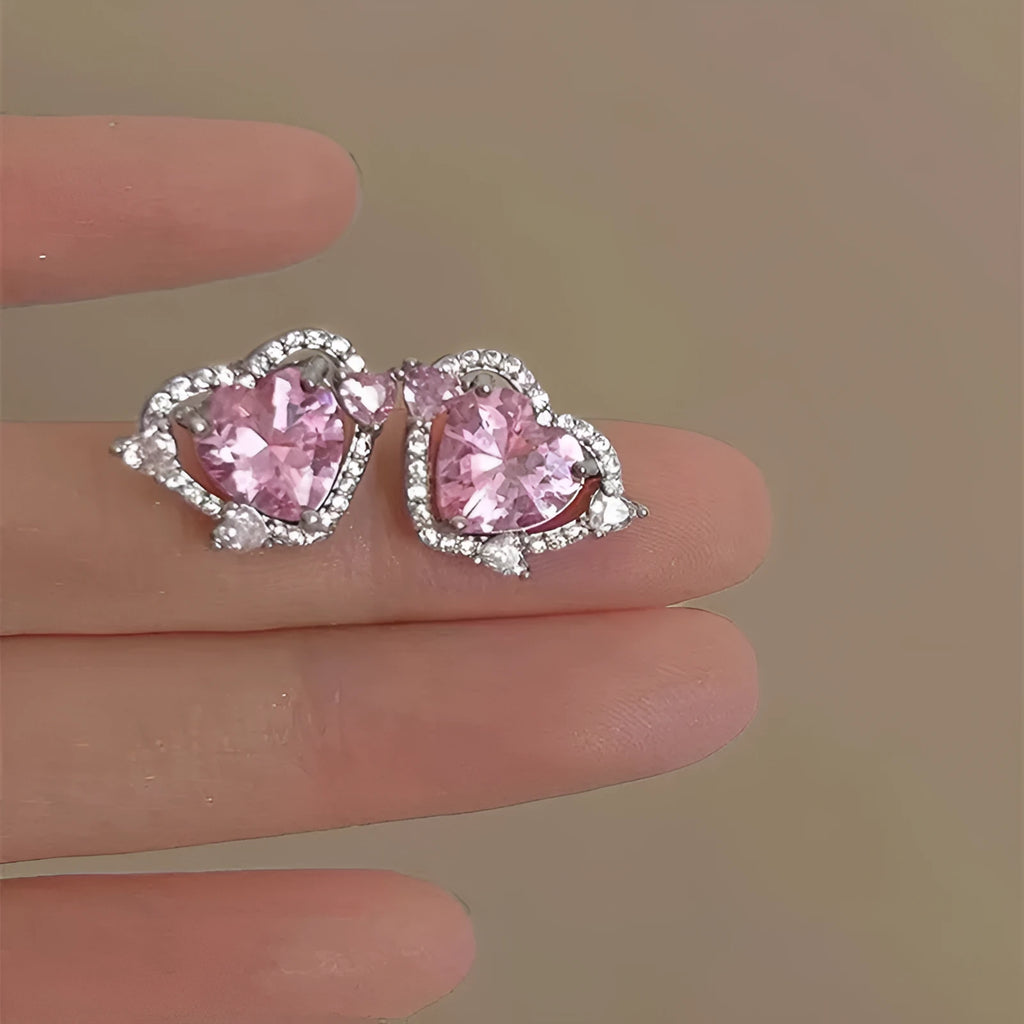 A pair of white heart-shaped stud earrings for women on a plain background.