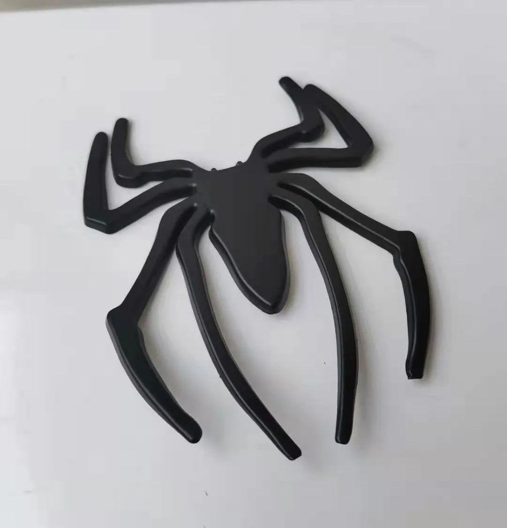 Three-dimensional metal spider bumper sticker in gold finish, measuring 7cm by 5cm.