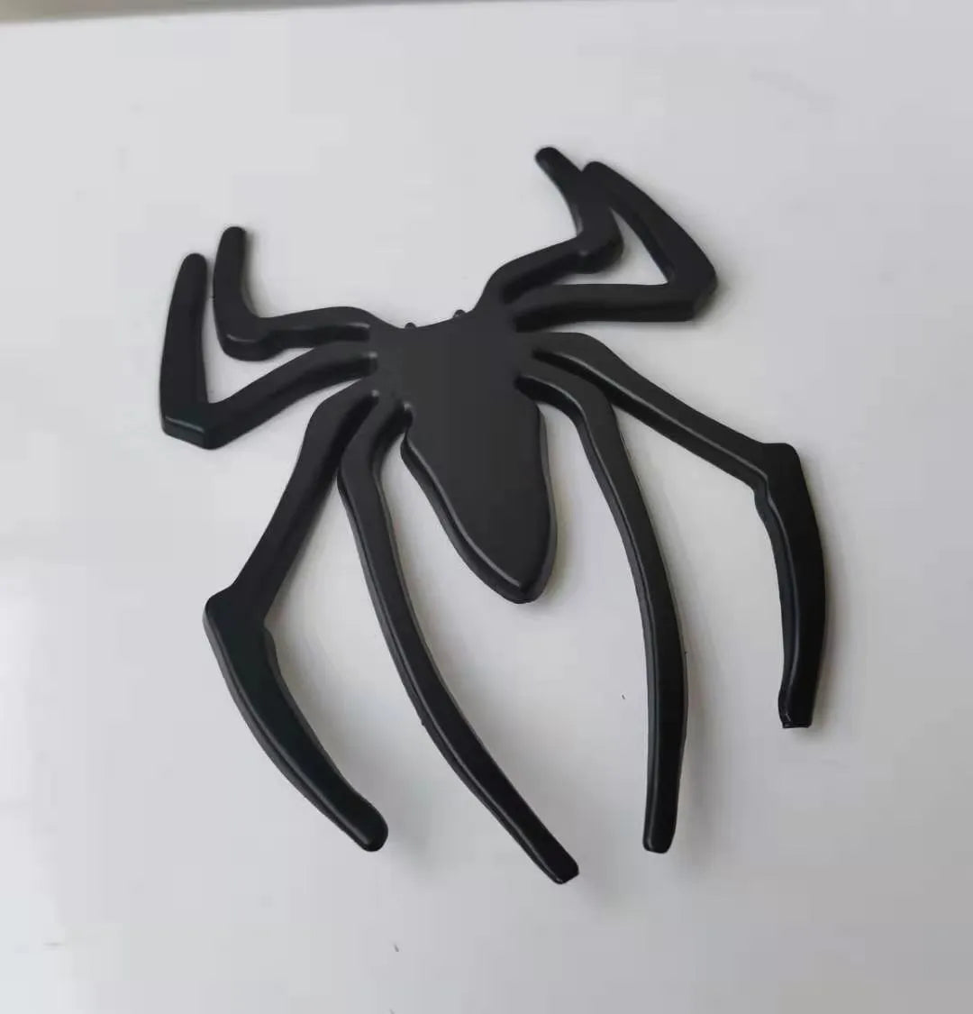 Three-dimensional metal spider bumper sticker in gold finish, measuring 7cm by 5cm.