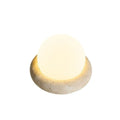 Cream-coloured modern bedside night light with remote control on a table.