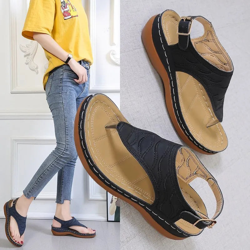Women's black wedge heel sandals with an adjustable back strap buckle on a white background.