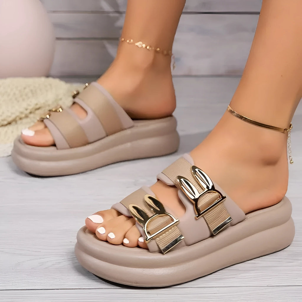 Women's apricot suede slippers with a thick, soft rubber sole on a wooden floor.
