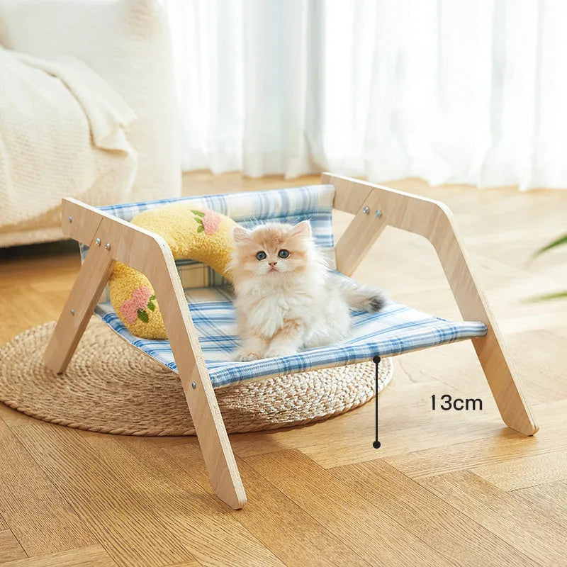 Green wooden elevated cat hammock bed with cloth sling on a light floor.