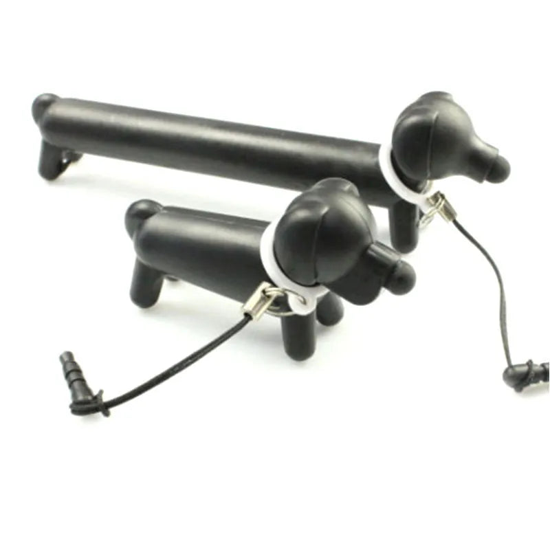 Black dog-shaped touch screen stylus pen shown next to a mobile phone on a desk.