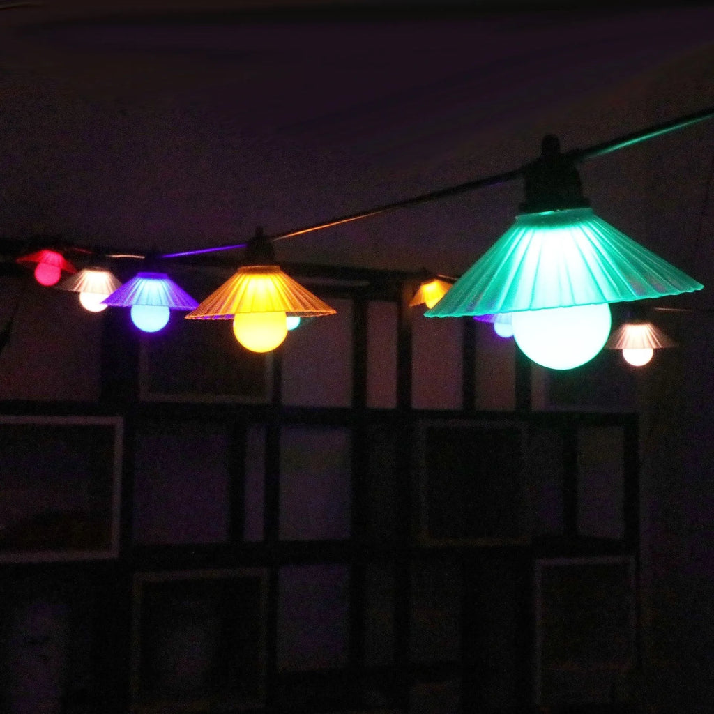 Outdoor LED string lights with flower-shaped bulbs hanging in a garden setting.