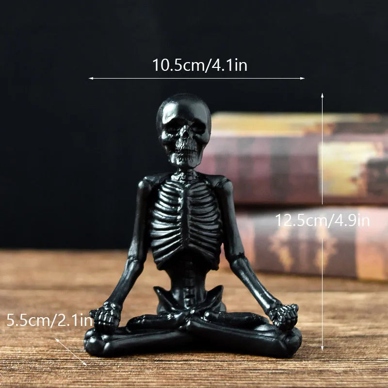 Detailed resin Halloween ornament of a yoga-posing skeleton skull on a desktop.