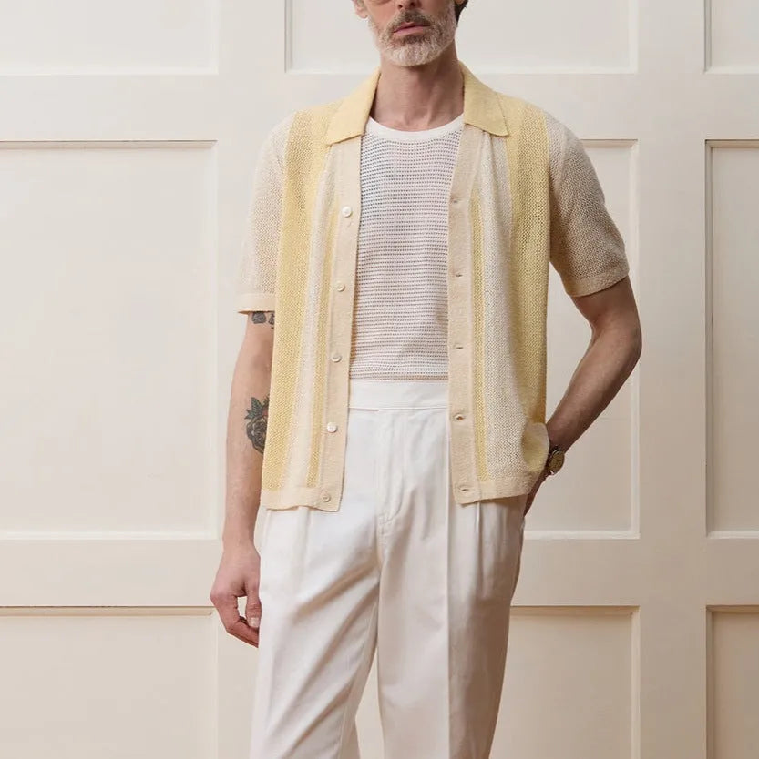 A bright yellow men's short-sleeved polo shirt with hollow-out asymmetric patterning on a casual model.