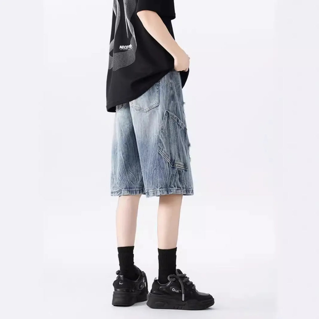 Man wearing black washed ripped denim shorts in a loose, retro style