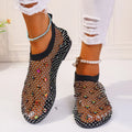 Women's flat sandals with colourful rhinestones on a mesh upper and rubber sole.